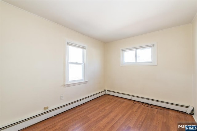 unfurnished room with baseboard heating, a healthy amount of sunlight, and light wood finished floors