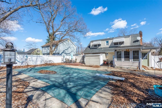 rear view of property with roof with shingles, fence, a sunroom, and a chimney