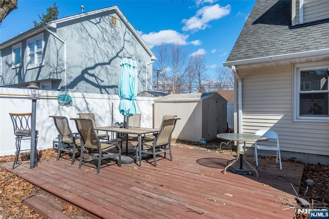 wooden deck with an outbuilding, a storage unit, and outdoor dining area