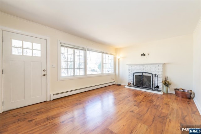 unfurnished living room with wood finished floors, a fireplace, baseboards, and baseboard heating