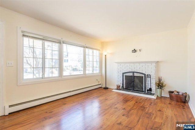 unfurnished living room featuring baseboards, ornamental molding, baseboard heating, a fireplace, and wood finished floors