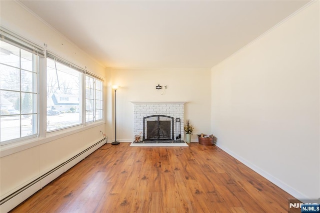 unfurnished living room featuring wood finished floors, a fireplace, baseboards, and a baseboard radiator