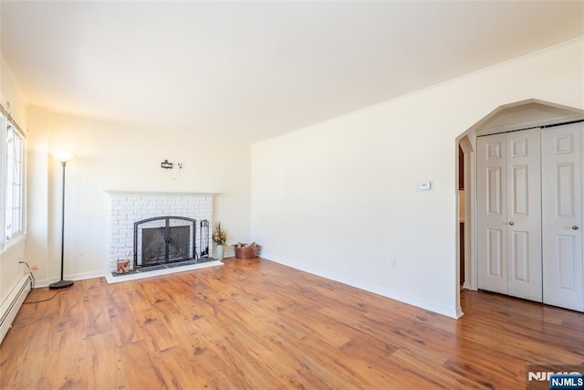 unfurnished living room with a baseboard radiator, baseboards, wood finished floors, and a fireplace