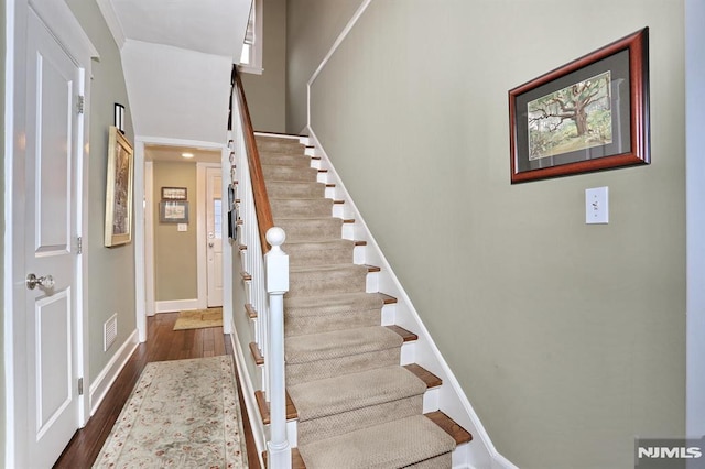 staircase with baseboards and wood finished floors