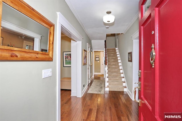 entryway featuring dark wood-type flooring, ornamental molding, baseboards, and stairs