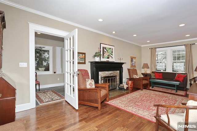 living room featuring a fireplace with flush hearth, french doors, ornamental molding, and wood finished floors