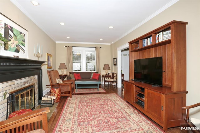 living room with ornamental molding, recessed lighting, a brick fireplace, and wood finished floors