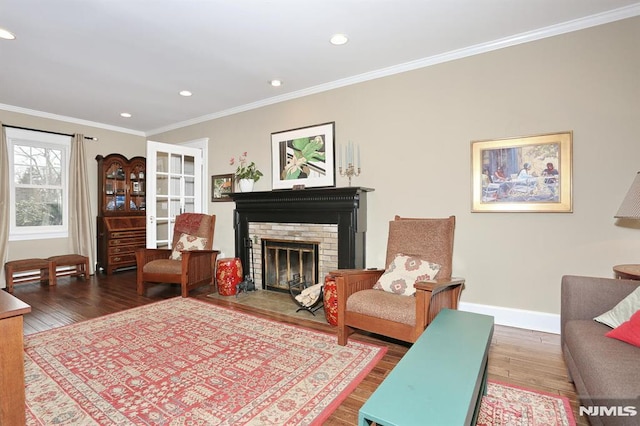 living area with recessed lighting, wood finished floors, baseboards, ornamental molding, and a brick fireplace