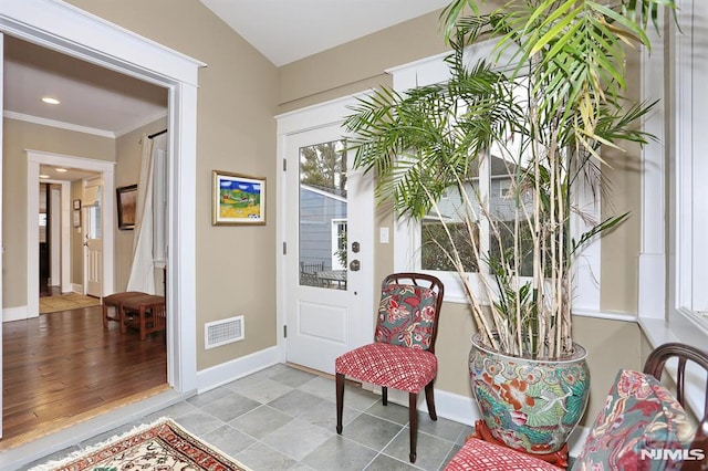 entrance foyer with baseboards, ornamental molding, visible vents, and a healthy amount of sunlight