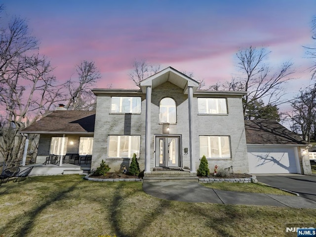 view of front of house featuring an attached garage, aphalt driveway, a front lawn, and brick siding