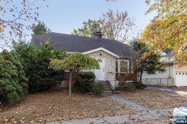 view of front of house featuring stone siding, brick siding, roof with shingles, and a chimney