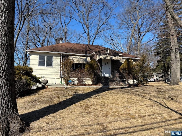 view of front of home with brick siding and a chimney