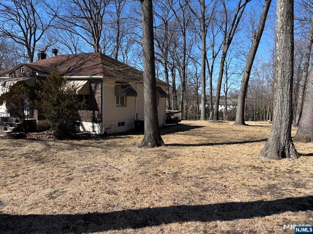 view of side of property featuring brick siding and crawl space