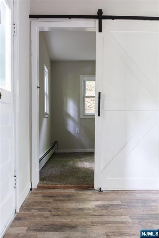 stairs with wood finished floors, baseboards, baseboard heating, and a barn door