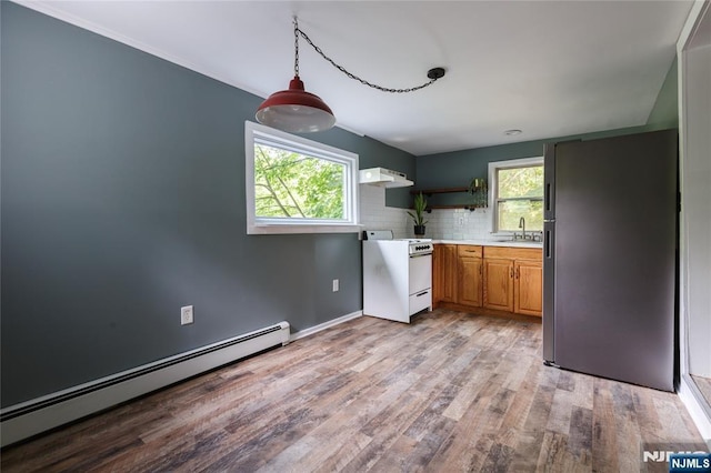 kitchen with white gas range, baseboard heating, freestanding refrigerator, a sink, and under cabinet range hood