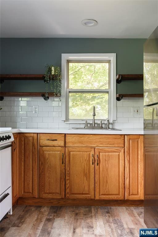 kitchen featuring electric range, a sink, light wood-type flooring, backsplash, and open shelves