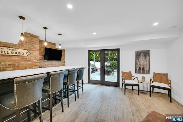 bar with a bar, decorative light fixtures, french doors, light wood-type flooring, and recessed lighting