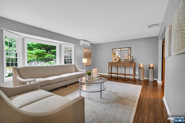 living room featuring an AC wall unit, visible vents, baseboards, and wood finished floors