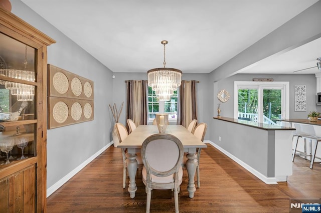 dining room featuring a notable chandelier, baseboards, and wood finished floors