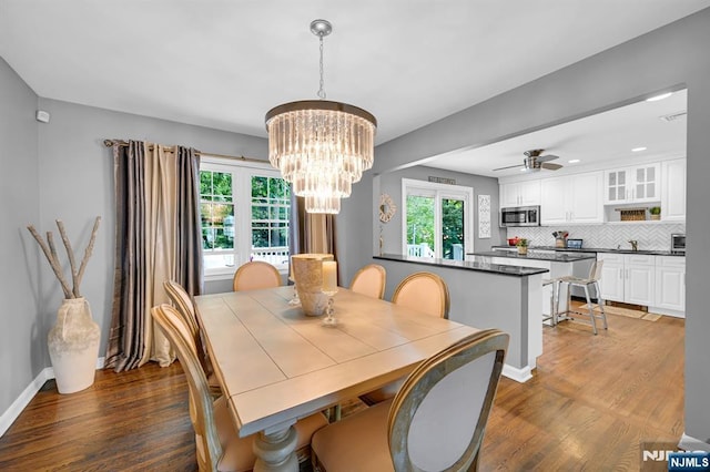 dining room featuring dark wood-style floors, baseboards, and ceiling fan with notable chandelier