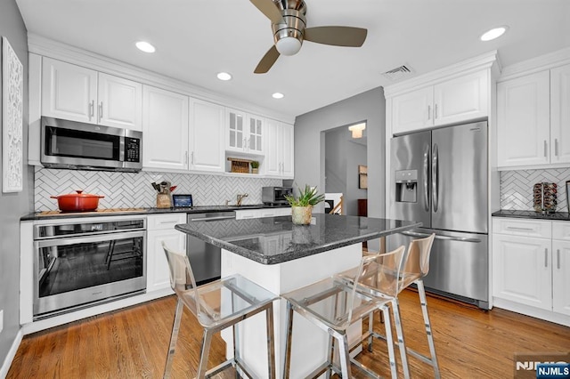 kitchen with stainless steel appliances, white cabinets, visible vents, and light wood finished floors