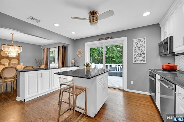 kitchen featuring a center island, a breakfast bar, visible vents, appliances with stainless steel finishes, and wood finished floors