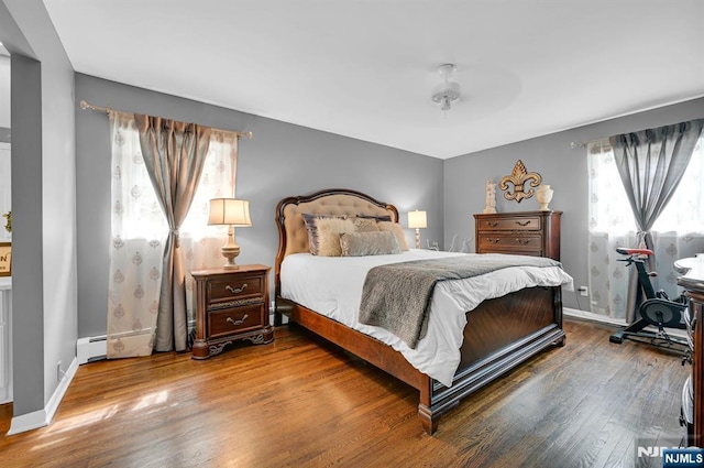 bedroom with ceiling fan, baseboards, baseboard heating, and wood finished floors