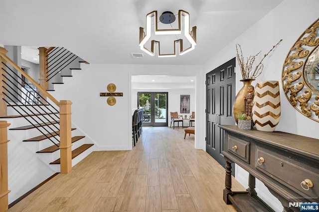 foyer featuring baseboards, visible vents, stairway, and light wood finished floors