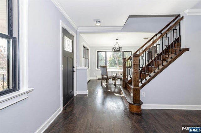 entryway with baseboards, stairway, ornamental molding, wood finished floors, and a notable chandelier