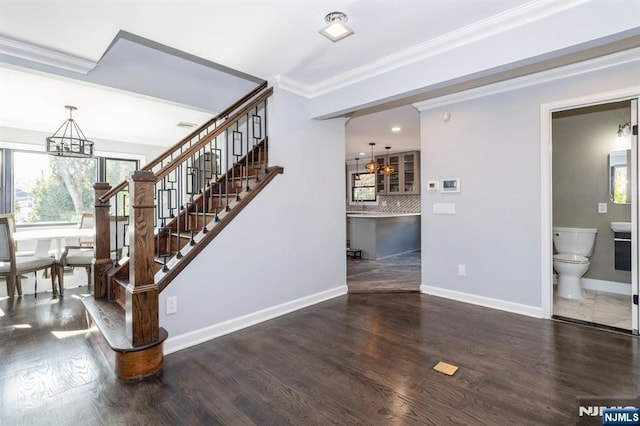 stairway featuring a chandelier, ornamental molding, wood finished floors, and baseboards