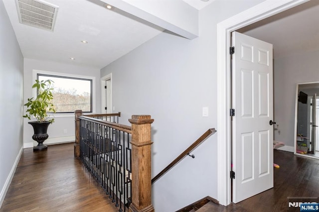 corridor with wood finished floors, an upstairs landing, visible vents, and baseboards