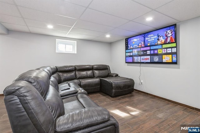 living room with wood finished floors, a paneled ceiling, and baseboards