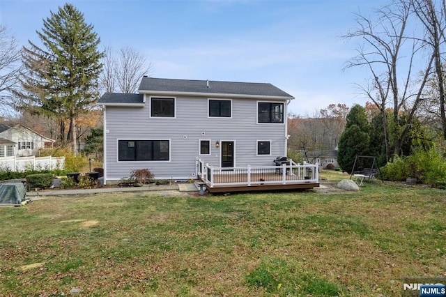 rear view of house with a deck and a yard