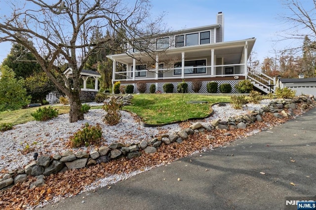 view of front of property featuring a porch, a front yard, and a chimney