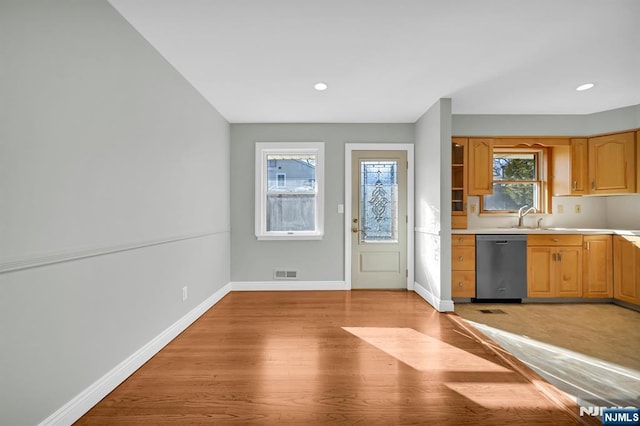 kitchen featuring light wood-style flooring, a sink, baseboards, light countertops, and dishwasher