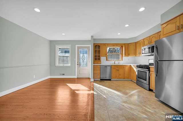 kitchen featuring baseboards, appliances with stainless steel finishes, light countertops, a sink, and recessed lighting