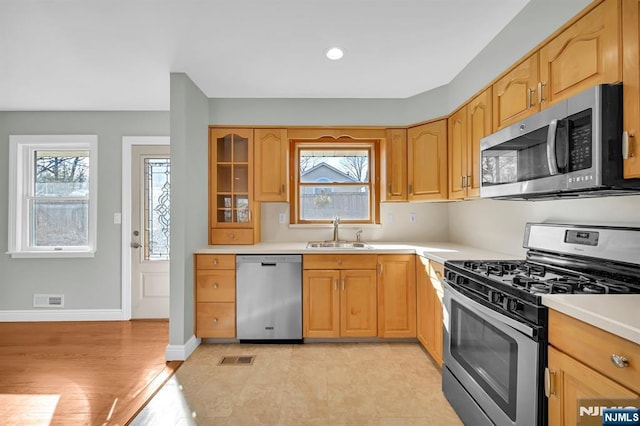 kitchen with light countertops, visible vents, appliances with stainless steel finishes, a sink, and baseboards