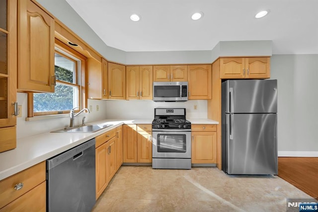 kitchen featuring stainless steel appliances, recessed lighting, light countertops, light brown cabinets, and a sink