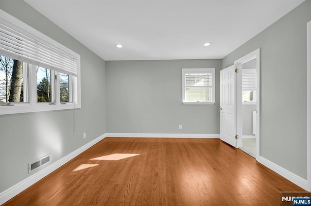 spare room featuring visible vents, baseboards, and wood finished floors