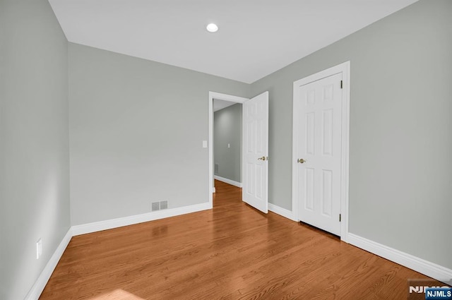 unfurnished bedroom with wood finished floors, visible vents, and baseboards