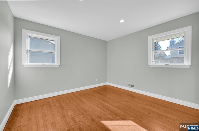 spare room with recessed lighting, visible vents, baseboards, and wood finished floors