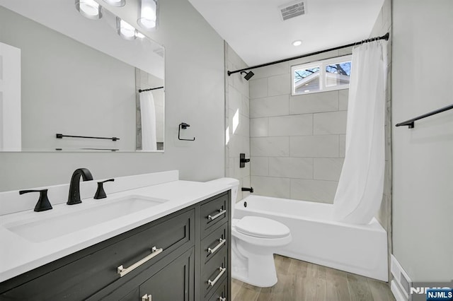 full bath featuring shower / bath combo, visible vents, toilet, wood finished floors, and vanity