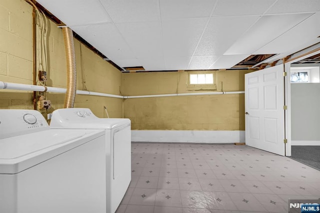 clothes washing area featuring laundry area, baseboards, light floors, and washing machine and clothes dryer