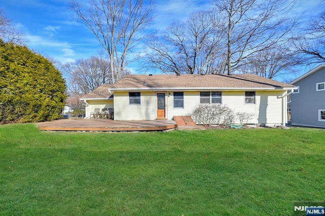 rear view of house with a deck and a yard