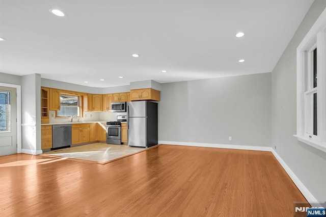 kitchen featuring appliances with stainless steel finishes, a sink, light wood-style flooring, and baseboards