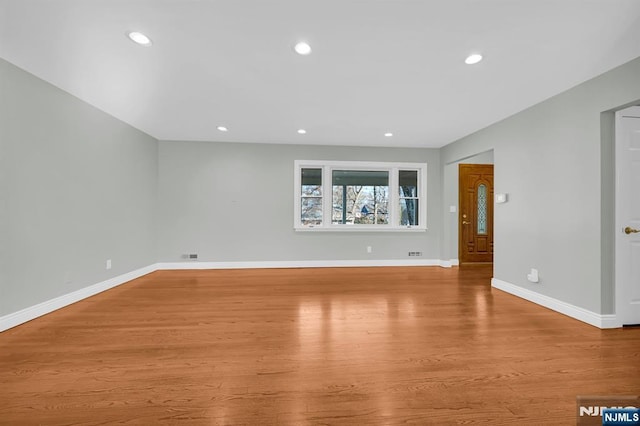 spare room featuring recessed lighting, baseboards, and wood finished floors