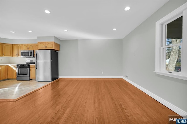 kitchen with light wood finished floors, baseboards, stainless steel appliances, light countertops, and recessed lighting