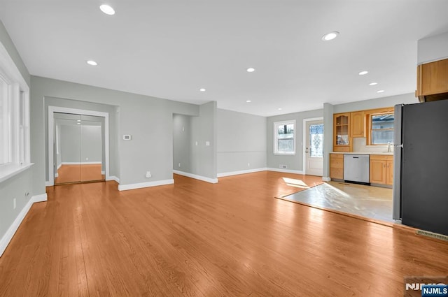 unfurnished living room featuring baseboards, light wood-type flooring, and recessed lighting