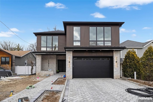 view of front of house with a garage, decorative driveway, fence, and stone siding