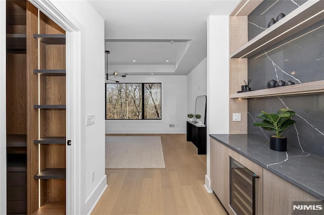 interior space featuring light wood finished floors, open shelves, a raised ceiling, decorative backsplash, and modern cabinets